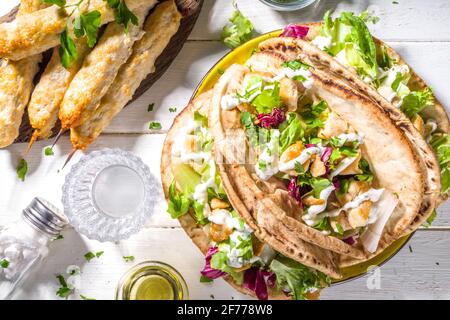 Cucina mediterranea. Doner Kebap, Taco, Shawarma, sandwich di gyros incartati greci, tortilla pita pane farcito carne di pollo alla griglia, verdure fresche, tsa Foto Stock