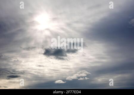 Un cielo sovrastato, la nuvola abbastanza sottile da consentire al sole di brillare debolmente attraverso e illuminare alcune nuvole di livello inferiore. Foto Stock