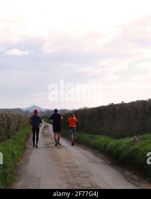 2021 aprile - tre corridori che si corrono verso il Tor a Glastonbury a Somerset, Regno Unito. Foto Stock