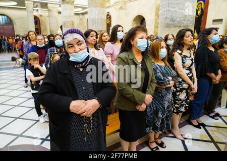 Mosul, Ninive, Iraq. 3 Apr 2021. I cristiani iracheni partecipano alla messa pasquale presso la Grande Immacolata Chiesa (al-Tahira-l-Kubra) nella città di Qaraqosh (al-Hamdaniya), a 30 chilometri a sud-est della città di Mosul. Pasqua è considerata la più grande e più grande festa cristiana, Commemora la risurrezione di Cristo dai morti dopo tre giorni della sua crocifissione e della sua morte, come scritto nel nuovo Testamento, in cui termina la Grande Quaresima che dura solitamente quaranta giorni. Durante la liturgia si cantano gli inni, si recita parte dell'Antico Testamento della Bibbia, gli inni dell'Hallelujah ar Foto Stock