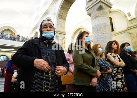 Mosul, Ninive, Iraq. 3 Apr 2021. I cristiani iracheni partecipano alla messa pasquale presso la Grande Immacolata Chiesa (al-Tahira-l-Kubra) nella città di Qaraqosh (al-Hamdaniya), a 30 chilometri a sud-est della città di Mosul. Pasqua è considerata la più grande e più grande festa cristiana, Commemora la risurrezione di Cristo dai morti dopo tre giorni della sua crocifissione e della sua morte, come scritto nel nuovo Testamento, in cui termina la Grande Quaresima che dura solitamente quaranta giorni. Durante la liturgia si cantano gli inni, si recita parte dell'Antico Testamento della Bibbia, gli inni dell'Hallelujah ar Foto Stock