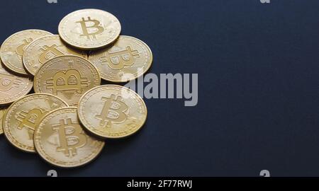 Primo piano di alcune monete di bit su uno sfondo blu scuro e spazio di copia. Monete d'oro BTC, mercato azionario delle criptovalute e finanze decentrate Foto Stock