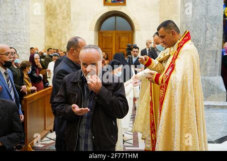 Mosul, Ninive, Iraq. 3 Apr 2021. I cristiani iracheni ricevono la Santa comunione durante la messa pasquale nella Grande Chiesa Immacolata (al-Tahira-l-Kubra) nella città di Qaraqosh (al-Hamdaniya), a 30 chilometri a sud-est della città di Mosul. Pasqua è considerata la più grande e più grande festa cristiana, Commemora la risurrezione di Cristo dai morti dopo tre giorni della sua crocifissione e della sua morte, come scritto nel nuovo Testamento, in cui termina la Grande Quaresima che dura solitamente quaranta giorni. Durante la liturgia si cantano gli inni, si recita parte dell'Antico Testamento della Bibbia, l'inno Foto Stock