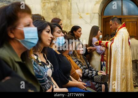 Mosul, Ninive, Iraq. 3 Apr 2021. I cristiani iracheni partecipano alla messa pasquale presso la Grande Immacolata Chiesa (al-Tahira-l-Kubra) nella città di Qaraqosh (al-Hamdaniya), a 30 chilometri a sud-est della città di Mosul. Pasqua è considerata la più grande e più grande festa cristiana, Commemora la risurrezione di Cristo dai morti dopo tre giorni della sua crocifissione e della sua morte, come scritto nel nuovo Testamento, in cui termina la Grande Quaresima che dura solitamente quaranta giorni. Durante la liturgia si cantano gli inni, si recita parte dell'Antico Testamento della Bibbia, gli inni dell'Hallelujah ar Foto Stock