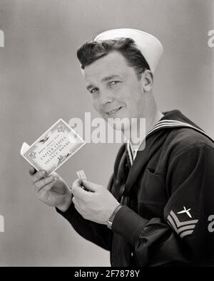 1940 SORRIDENTE MARINAIO DELLA MARINA GUARDANDO LA MACCHINA FOTOGRAFICA CHE TIENE LA GUERRA MONDIALE 2 OPUSCOLO E TIMBRO DEL PIANO POSTALE SULLE OBBLIGAZIONI DI RISPARMIO DEGLI STATI UNITI - D1634 HAR001 HARS STUDIO SHOT NAVY STATI UNITI COPIA SPAZIO MEZZA LUNGHEZZA PERSONE POSTALI STATI UNITI D'AMERICA FORZA MASCHILE B&W BOND NORD AMERICA OCCHIO CONTATTO OBIETTIVI DI LIBERTÀ NORD AMERICA ALLEGRA GUERRA NAVALE E MONDIALE GUERRA MONDIALE GUERRA MONDIALE GUERRA MONDIALE DUE LA SECONDA GUERRA MONDIALE SORRIDE UNIFORMI FORZA LIBRETTO GIOIOSO NAVIE PATRIOTTICHE GUERRA MONDIALE 2 USN GIOVANE UOMO ADULTO NERO E BIANCO ETNIA CAUCASICA HAR001 VECCHIO STILE Foto Stock