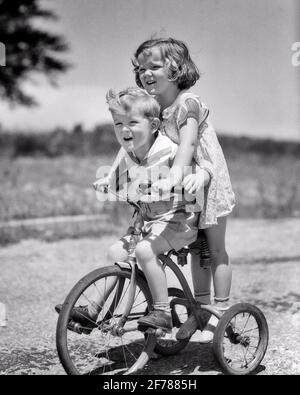 ANNI '30 SORELLA DI FRATELLO DI RAGAZZO E RAGAZZA CHE CAVALCANO TANDEM SUL TRICICLO RAGAZZA CHE GUIDA SULLA PARTE POSTERIORE DI TRIKE RAGAZZO PEDDLING RIDENDO AVENDO FUN - J6278 HAR001 HARS RURAL SPAZIO COPIA VITA DOMESTICA A LUNGHEZZA INTERA SEMI-LUNGHEZZA MASCHI FRATELLI BICICLETTE SORELLE TRASPORTO B&W BICICLETTE IN ESTATE TRICICLO E BASSO ANGOLO DI SUL FRATELLO PEDDLING STAGIONE GIOVANILE TRIKE NERO E BIANCO ETNIA CAUCASICA HAR001 VECCHIO STILE Foto Stock