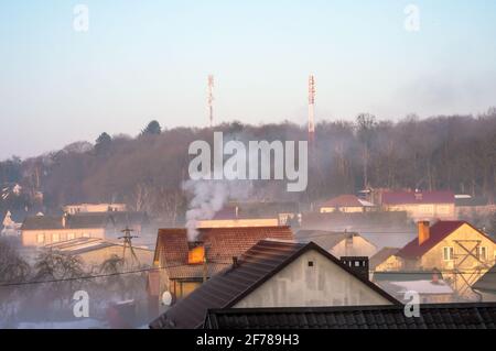 Russia, regione di Kaliningrad, 22 febbraio 2021. Tetti di case di villaggio. Nebbia sopra le case del villaggio. Fumo dal camino. Foto Stock