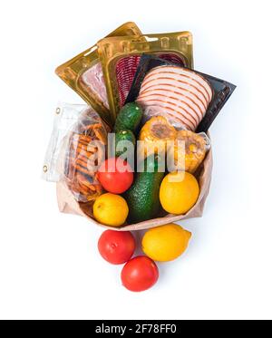 Pomodori, cetrioli, mais, salsiccia e cracker di pomodoro in una borsa di carta. Il sacchetto con i prodotti è isolato su fondo bianco. Visto in alto. Foto Stock