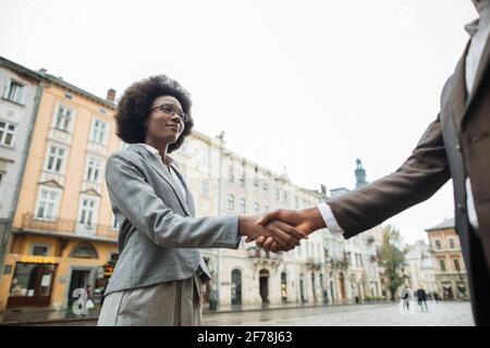 Colleghi africani di successo in abito formale si salutano l'un l'altro con la mano scuotendo sulla strada. Concetto di cooperazione e partenariato. Foto Stock