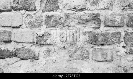 Sfondo grigio muro di mattoni, vecchio muro di mattoni parzialmente coperto da cemento. Foto Stock