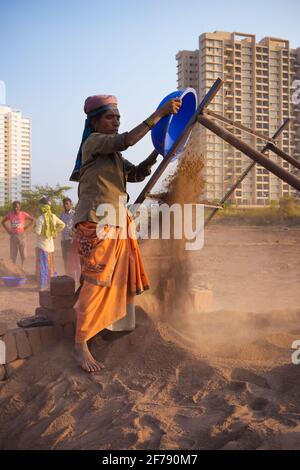 Donna indiana che versa il suolo sul setacciatore di suolo, lavorando in mattone forno sito Foto Stock