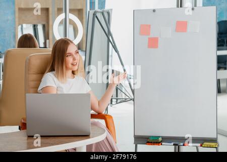 L'insegnante online registra le lezioni video. Il manager effettua la presentazione durante la riunione online. Donna vicino a lavagna bianca con computer portatile. Coach mentor blogger influenza Foto Stock