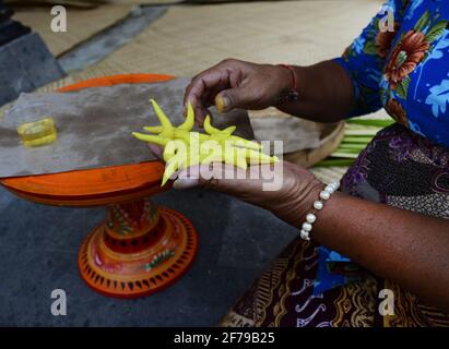Donna balinese che prepara un'offerta fatta a mano chiamata Jajan Suci o Palegembai in un tempio indù a Bali, Indonesia. Foto Stock