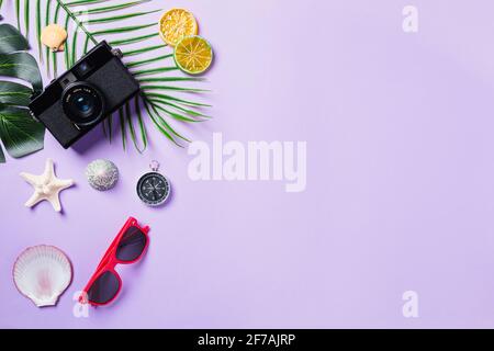 Vista dall'alto mock-up piatto di pellicole per fotocamere, conchiglie, foglie, Starfish Beach Traveler accessori su sfondo viola con spazio per la copia, viaggio d'affari, A. Foto Stock