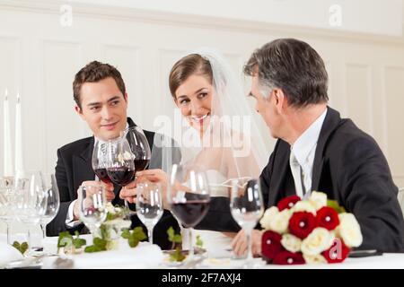 Festa di nozze a cena - la coppia nuziale è clking bicchieri con vino Foto Stock