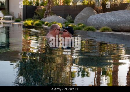 Due gay si divertono l'uno con l'altro in una piscina a Palm Springs, Riverside County, California, USA. Foto Stock