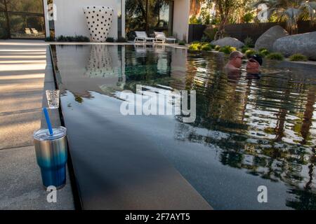 Due gay si divertono l'uno con l'altro in una piscina a Palm Springs, Riverside County, California, USA. Foto Stock