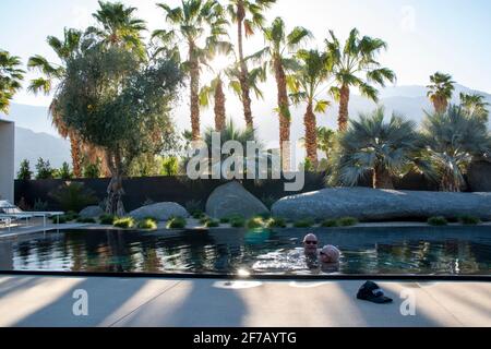 Due gay si divertono l'uno con l'altro in una piscina a Palm Springs, Riverside County, California, USA. Foto Stock