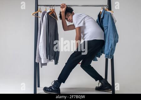 Giovane ragazzo afroamericano che tiene appendiabiti e si appoggia avanti Foto Stock