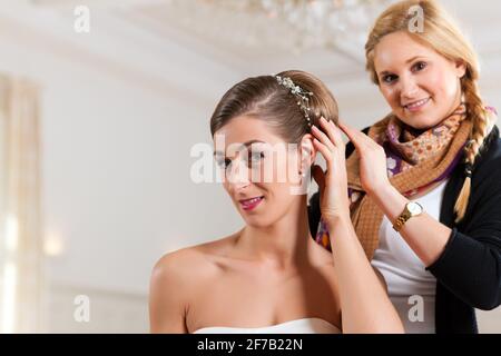 La stilista pinning di una sposa acconciatura prima del matrimonio Foto Stock