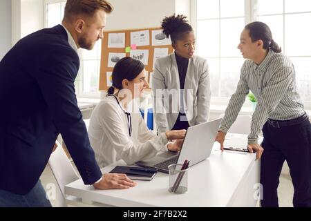 Gruppo di uomini d'affari multirazziali che discutono di progetto, condividendo idee e usando il laptop Foto Stock