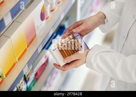 Fiale in vetro con liquido marrone trasparente per terapia medica. Primo piano di ampolle tenute dalle mani femminili delicate di un farmacista in uno zio Foto Stock