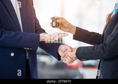 mano di donna di vendite di automobile che dà la chiave del Nuova auto al e scuotendo le mani con i clienti Foto Stock