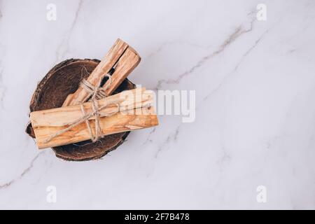 Palo Santo bastoni all'interno conchiglia di cocco su sfondo di tavola di marmo chiaro - albero sacro di incenso dall'America Latina. Meditazione, salute mentale e. Foto Stock