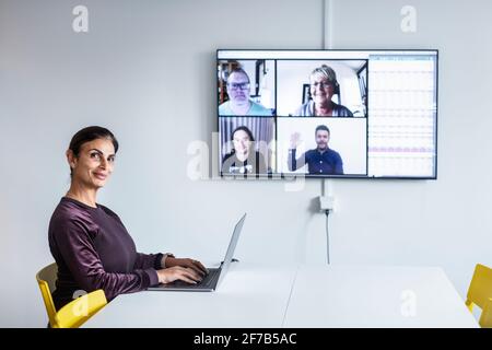 Donna in sala riunioni con videoconferenza Foto Stock