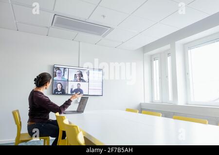 Donna in sala riunioni con videoconferenza Foto Stock