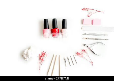 Strumenti di una manicure su sfondo bianco. Bottiglie di smalto per unghie e utensili intorno. Foto Stock