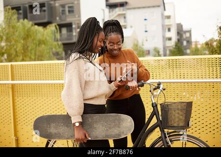 Amici di sesso femminile guardando al telefono cellulare Foto Stock