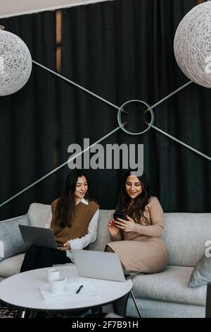 Donne che si siedono sul divano Foto Stock