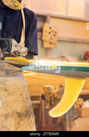 Primo piano di un artigiano africano tavola da surf Shaper lavorare in un'officina di riparazione Foto Stock