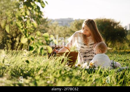 Genitori mamma e figlia ad un picnic sedersi su erba verde nel campo. Foto Stock