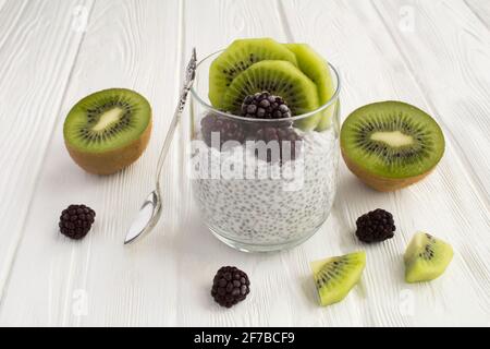 Pudding con chia, kiwi e mora su sfondo di legno bianco Foto Stock