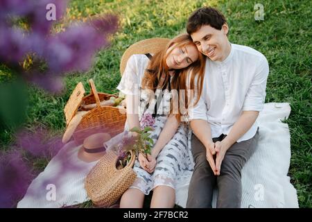 Felice coppia innamorato su un picnic, si siede riposando sull'erba verde. Foto Stock