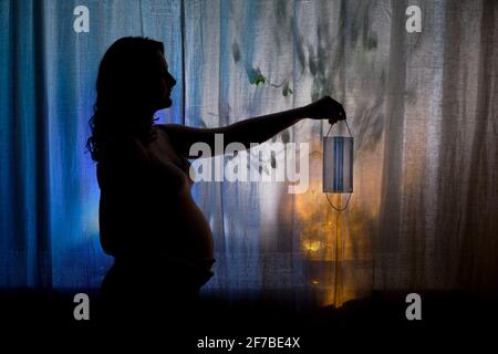 Ombra di una donna incinta che prende via la sua maschera medica dopo il recupero. Problemi di gravidanza con una pandemia del virus dell'influenza Foto Stock