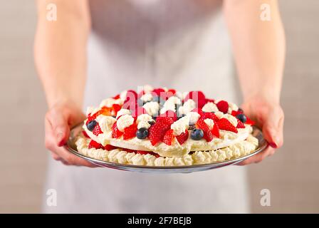 Mani femminili che tengono in casa torta di fragole, torta. Self made sano concetto di dessert Foto Stock