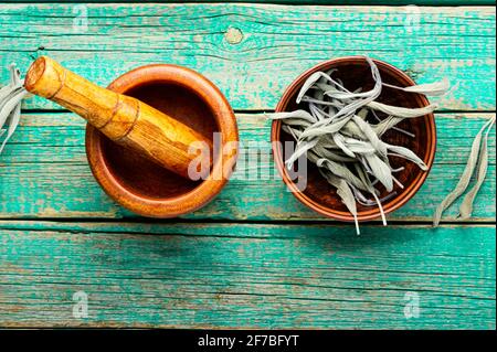 Foglie di salvia essiccate su tavola rustica di legno Foto Stock