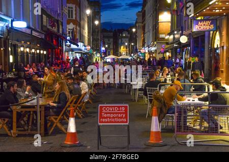 Folla di persone su Old Compton Street, Soho di notte. Sono stati implementati dei posti a sedere temporanei all'aperto per consentire ai bar e ai ristoranti di operare e facilitare l'allontanamento sociale durante la pandemia del coronavirus. Londra, Regno Unito, 28 settembre 2020. Foto Stock