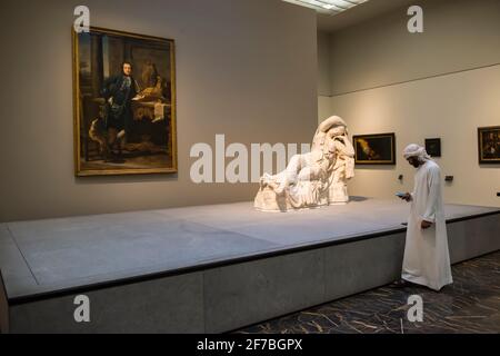 Cliente arabo che guarda il suo smartphone in una sala espositiva del museo del Louvre. Abu Dhabi, Emirati Arabi Uniti. Foto Stock