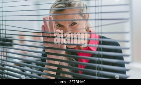 close up. una donna d'affari guarda attraverso le finestre persiane. Foto Stock