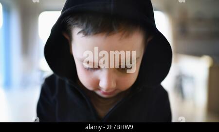 Povero ragazzo triste con sopracciglia tagliata in piedi in casa, concetto di povertà. Foto Stock