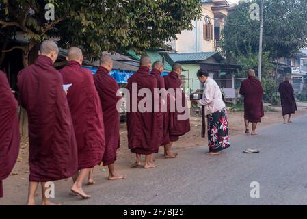 Monaci che camminano per le strade di Bago raccogliere donazioni di cibo, Bago, Myanmar Foto Stock