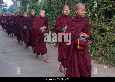 Monaci che camminano per le strade di Bago raccogliere donazioni di cibo, Bago, Myanmar Foto Stock