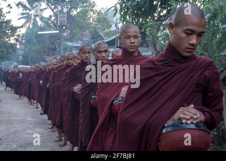 Monaci che camminano per le strade di Bago raccogliere donazioni di cibo, Bago, Myanmar Foto Stock