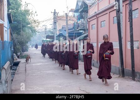 Monaci che camminano per le strade di Bago raccogliere donazioni di cibo, Bago, Myanmar Foto Stock