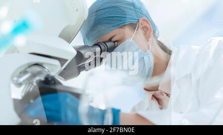 scienziata femminile che usa un microscopio in un laboratorio medico. Foto Stock