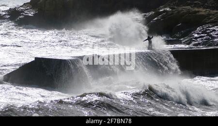 La gente cerca di evitare onde che si schiantano sulle pareti a Cullercoats vicino Tynemouth. Data immagine: Martedì 6 aprile 2021. Foto Stock